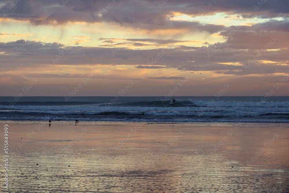 Fototapeta premium surfer riding wave at sunrise