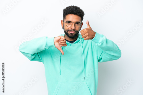 Young Brazilian man isolated on white background making good-bad sign. Undecided between yes or not © luismolinero