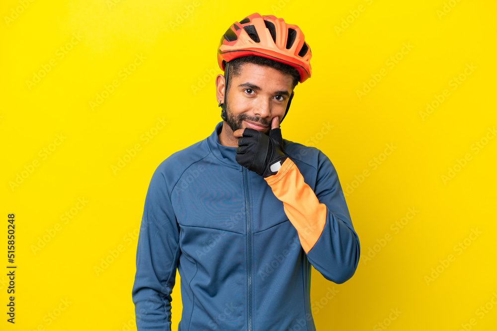 Young cyclist Brazilian man isolated on yellow background thinking Young cyclist Brazilian man isolated on yellow background thinking