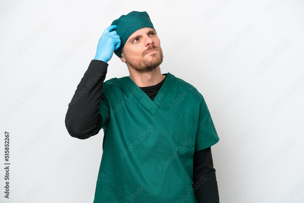 Surgeon Brazilian man in green uniform isolated on white background having doubts and with confuse face expression
