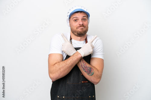 Fishmonger man wearing an apron isolated on white background pointing to the laterals having doubts