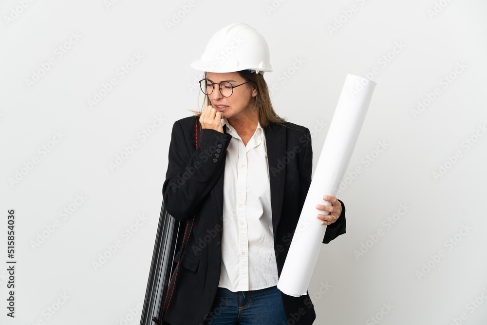 Middle age architect woman with helmet and holding blueprints over isolated background having doubts Middle age architect woman with helmet and holding blueprints over isolated background having doubts
