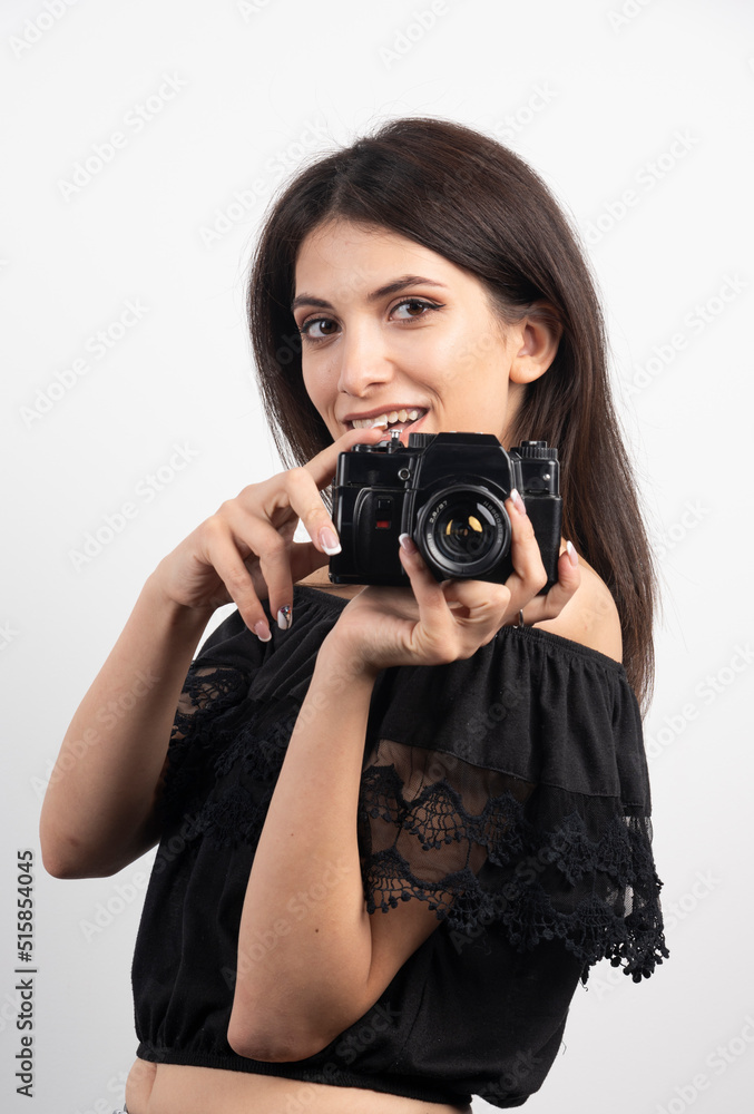Pretty woman standing with a camera on white background Pretty woman standing with a camera on white background