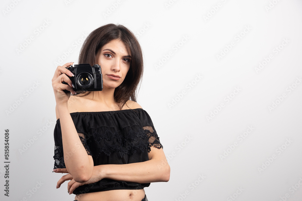Serious looking woman holding camera on white background Serious looking woman holding camera on white background