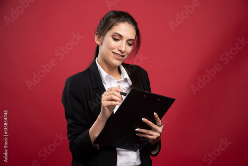 Young businesswoman checking avaible dates on red background photo