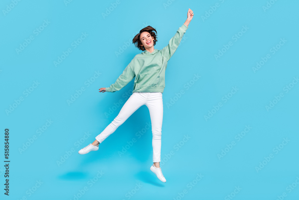 Full body photo of cool young brunette lady jump wear hoodie pants sneakers isolated on blue background