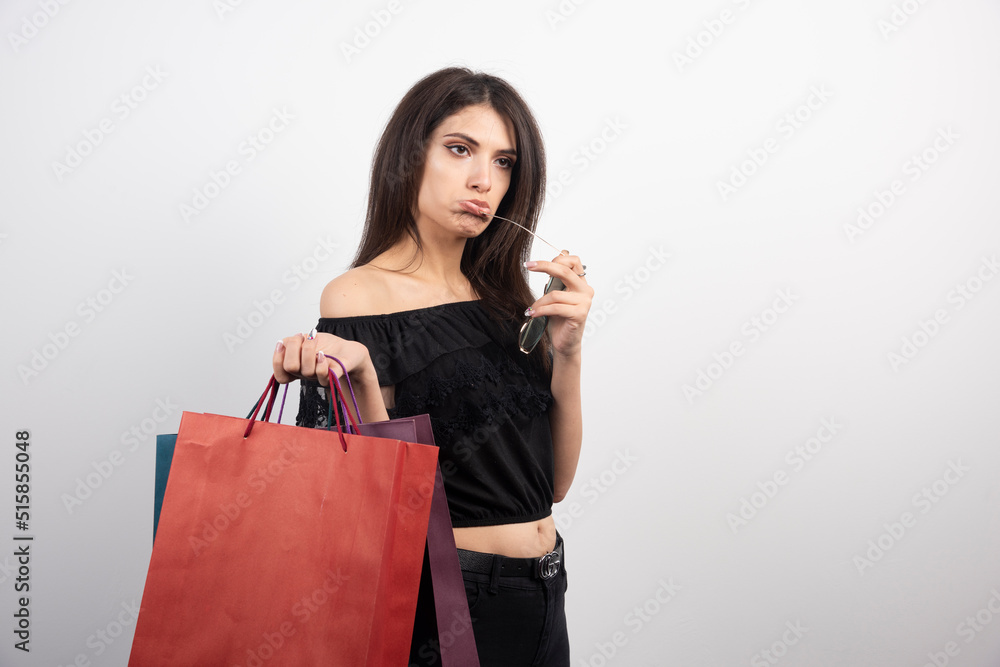 Brunette woman holding shopping bags and glasses on white background Brunette woman holding shopping bags and glasses on white background