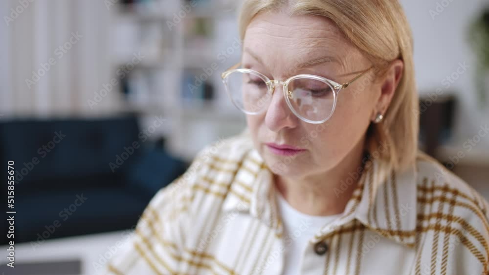 Focused woman in her 50s examining contract on paper, home office, entrepreneur Focused woman in her 50s examining contract on paper, home office, entrepreneur