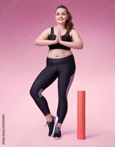 Young girl ready to yoga. Photo of pretty model with curvy figure in black sportswear on pink background. Sports motivation and healthy lifestyle © Romario Ien