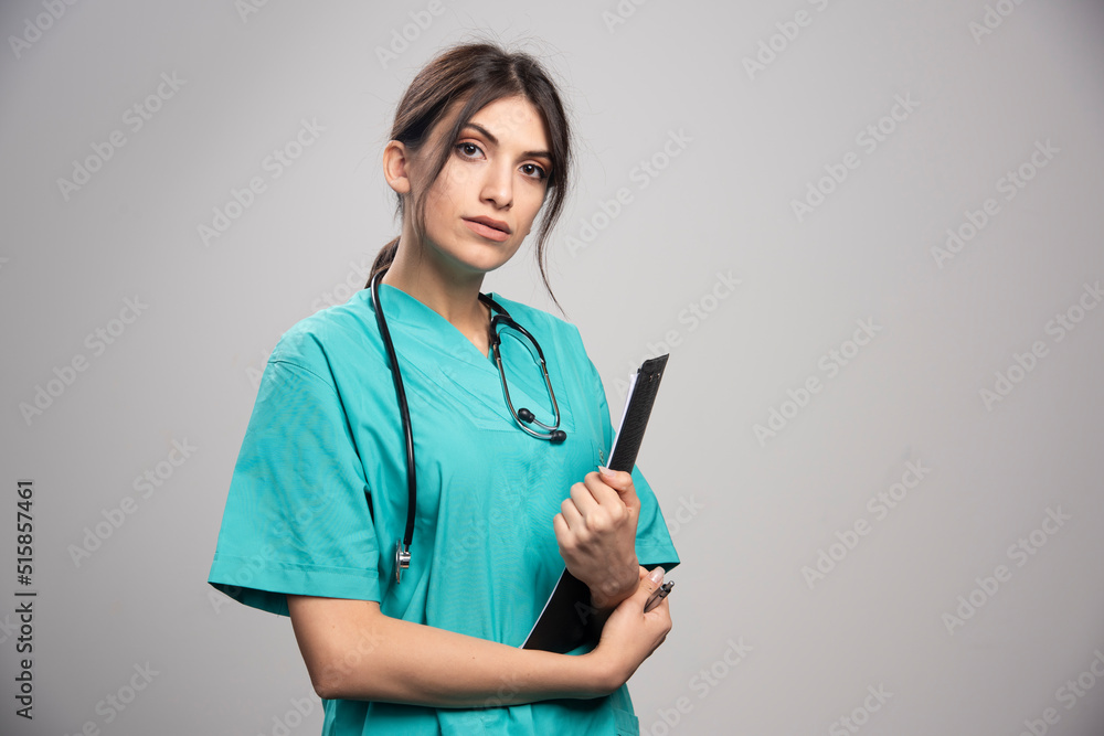 Female doctor holding clipboard on gray background Female doctor holding clipboard on gray background