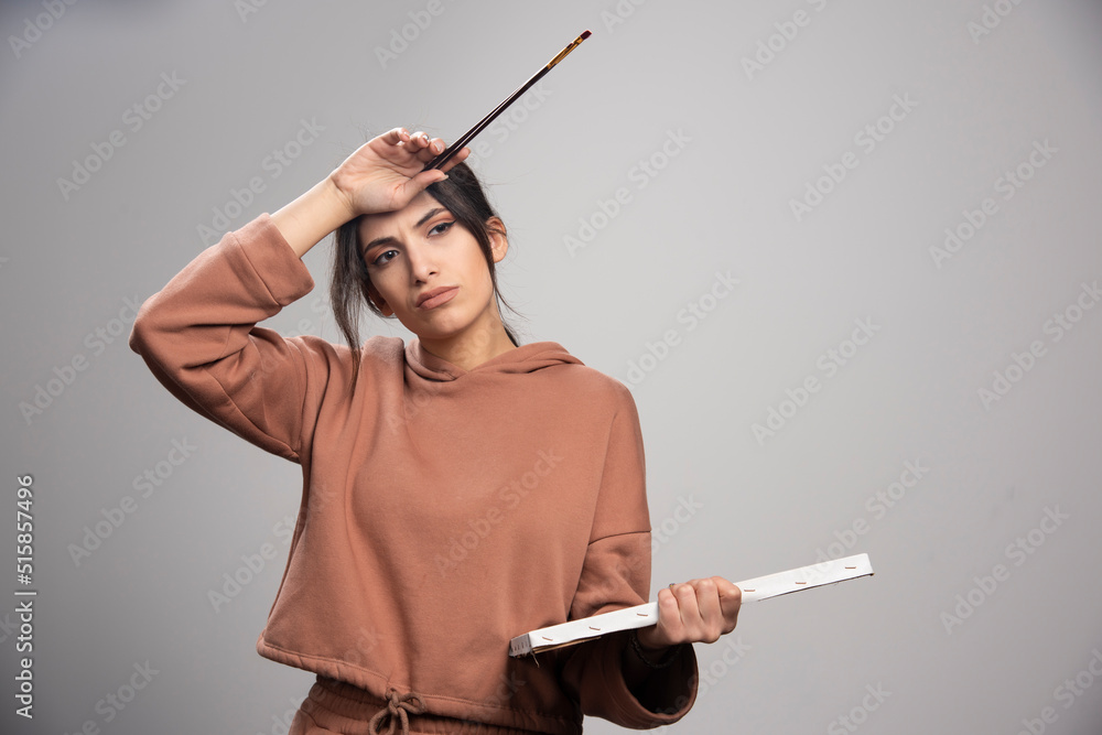 Young beautiful artist holding paint brush and canvas Young beautiful artist holding paint brush and canvas