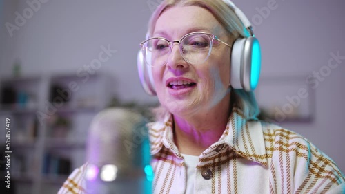 Close-up of beautiful senior woman recording podcast, radio anchor, announcer photo