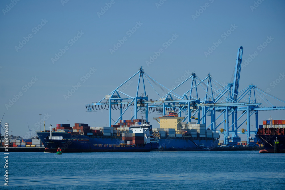 ROTTERDAM, THE NETHERLANDS - New container terminal with a very large container ship and in the foreground a smaller inland container ship on the Maasvlakte of the port of Rotterdam ROTTERDAM, THE NETHERLANDS - New container terminal with a very large container ship and in the foreground a smaller inland container ship on the Maasvlakte of the port of Rotterdam