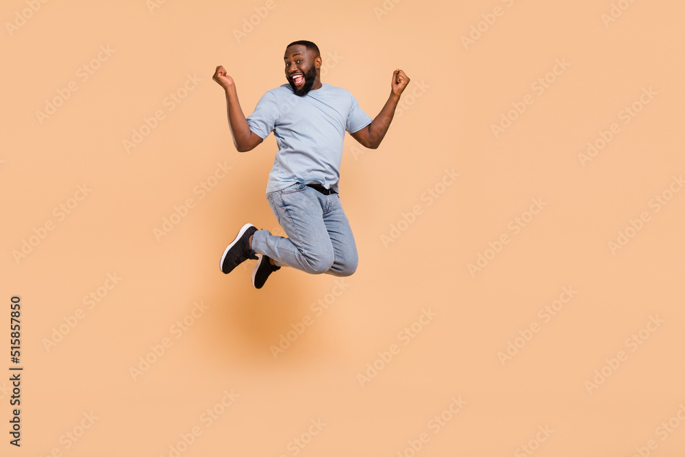 Full length body size view of attractive cheerful guy jumping rejoicing having fun isolated over beige pastel color background