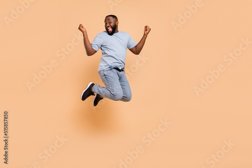 Full length body size view of attractive cheerful guy jumping rejoicing having fun isolated over beige pastel color background