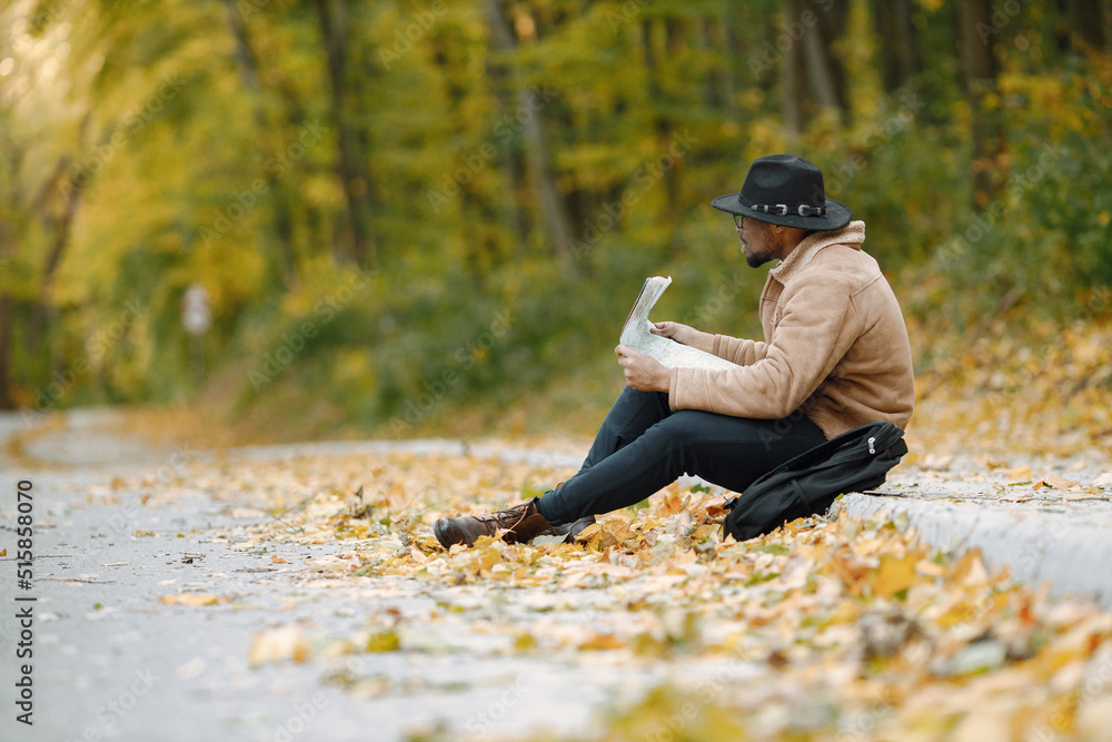 Black man sitting on a road and looking at map Black man sitting on a road and looking at map