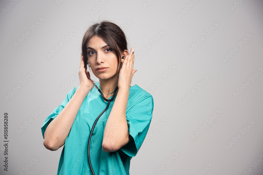 Female doctor with stethoscope standing on gray background Female doctor with stethoscope standing on gray background