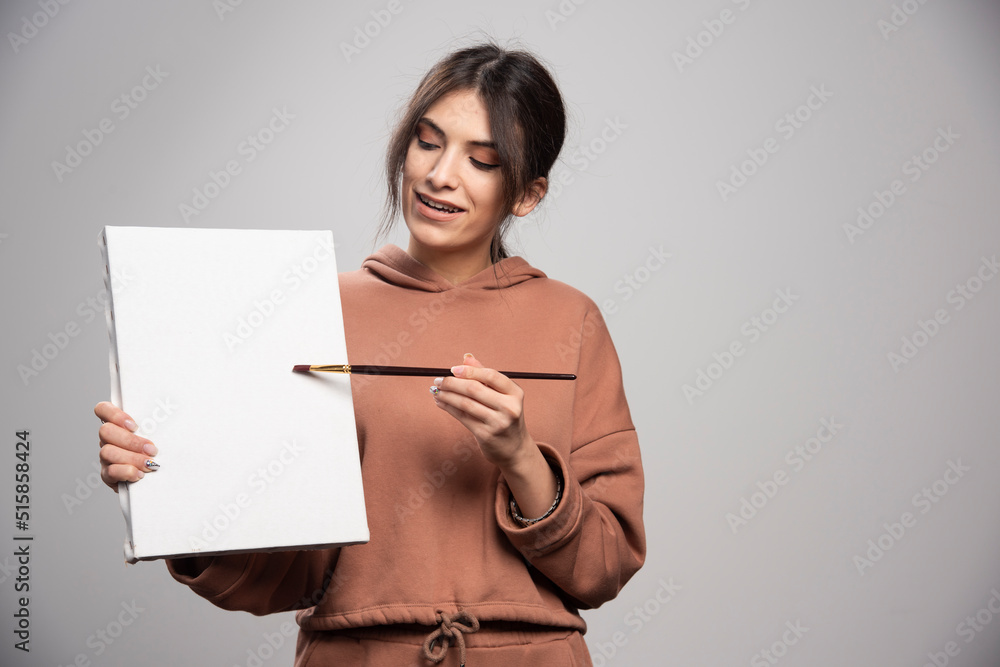Naklejka premium Female painter posing with paint brushe and canvas