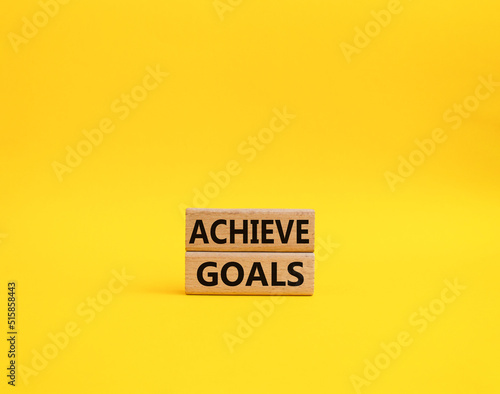 Achieve goals symbol. Concept words achieve goals on wooden blocks. Beautiful yellow background. Business and achieve goals concept. Copy space.