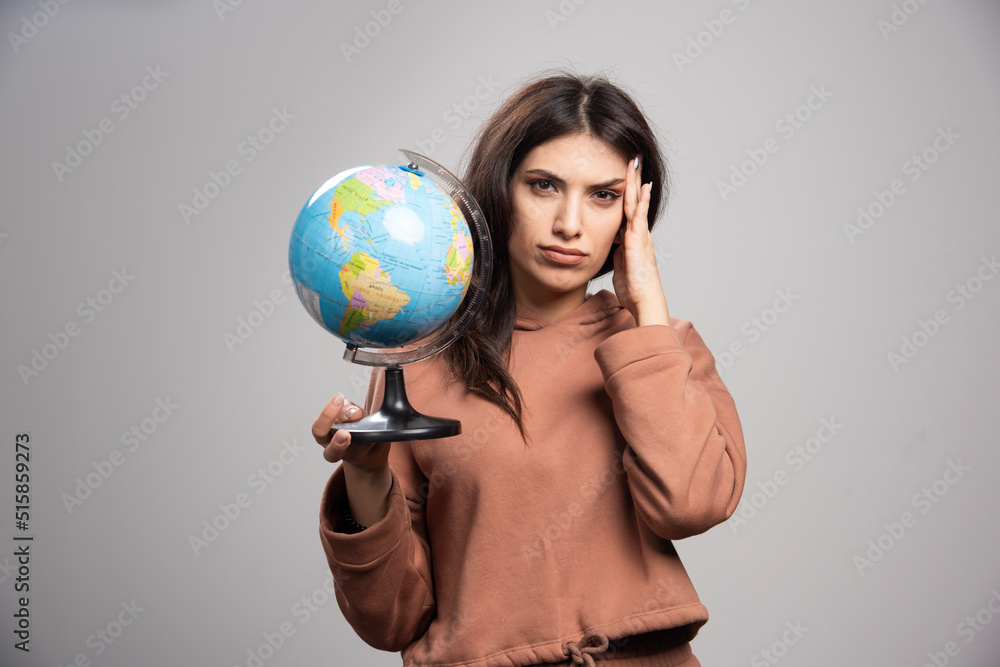 Brunette woman holding globe on gray background Brunette woman holding globe on gray background