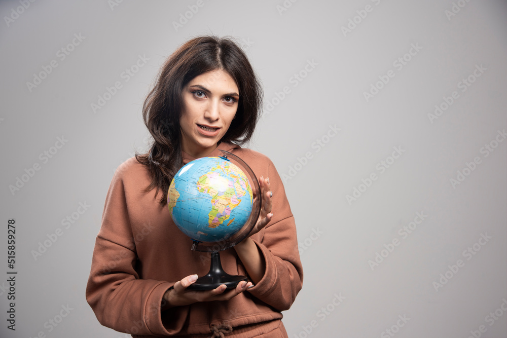 Brunette woman holding globe on gray background Brunette woman holding globe on gray background
