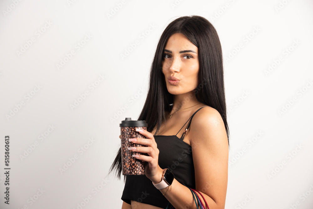 Portrait of woman holding cup of coffee on beige background Portrait of woman holding cup of coffee on beige background