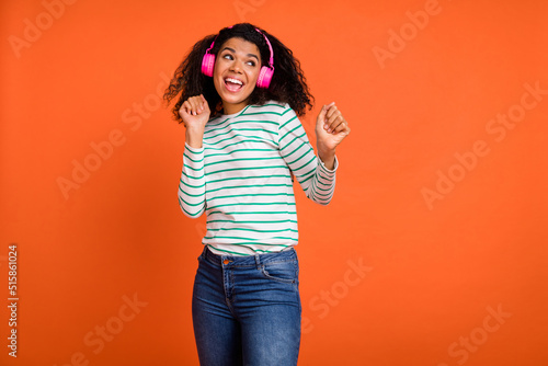 Photo of millennial lady dance look ad wear earphones shirt jeans isolated on orange background