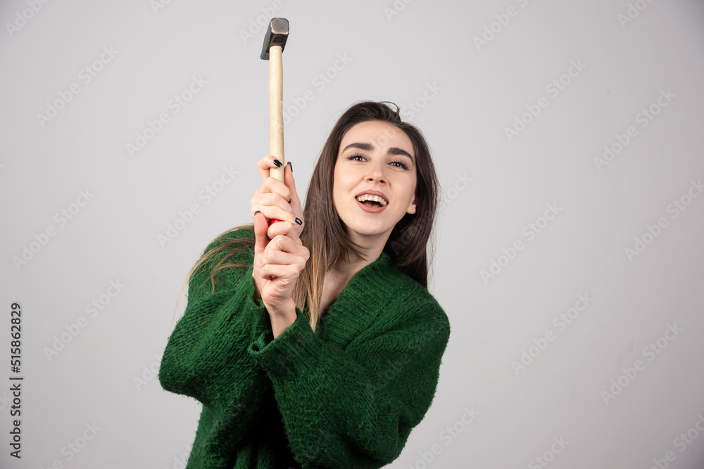 Pensive woman holding hammer in hands on a gray background Pensive woman holding hammer in hands on a gray background