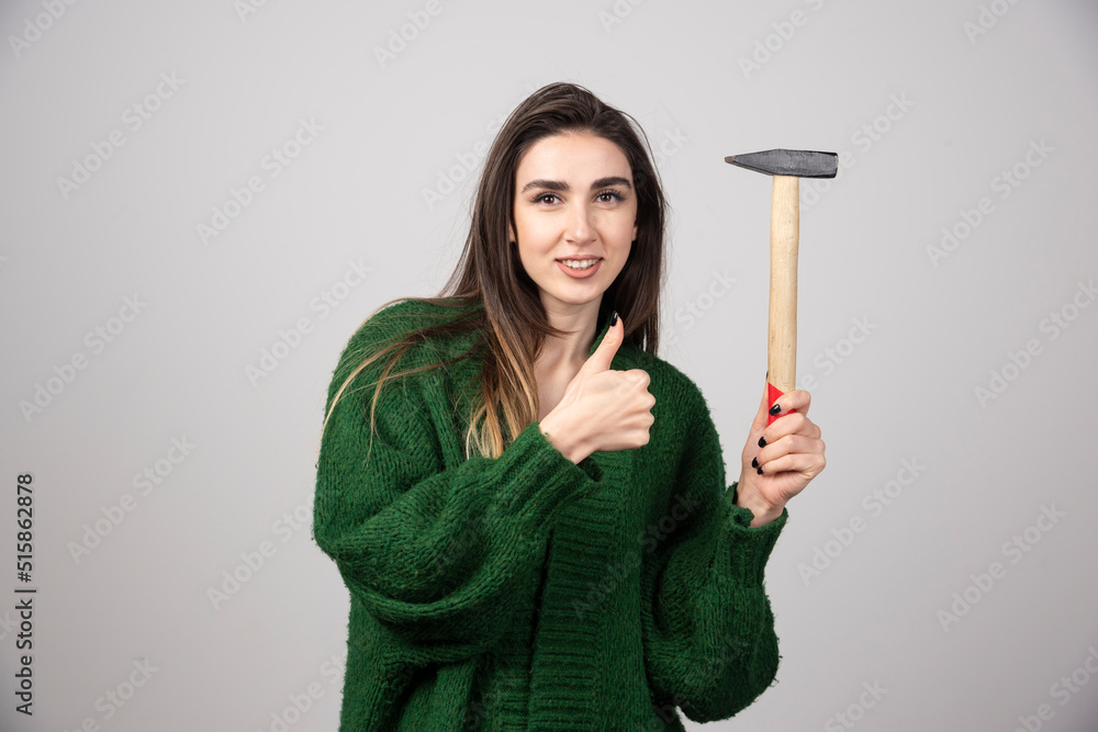 A young woman holding a hammer and showing a thumb up A young woman holding a hammer and showing a thumb up