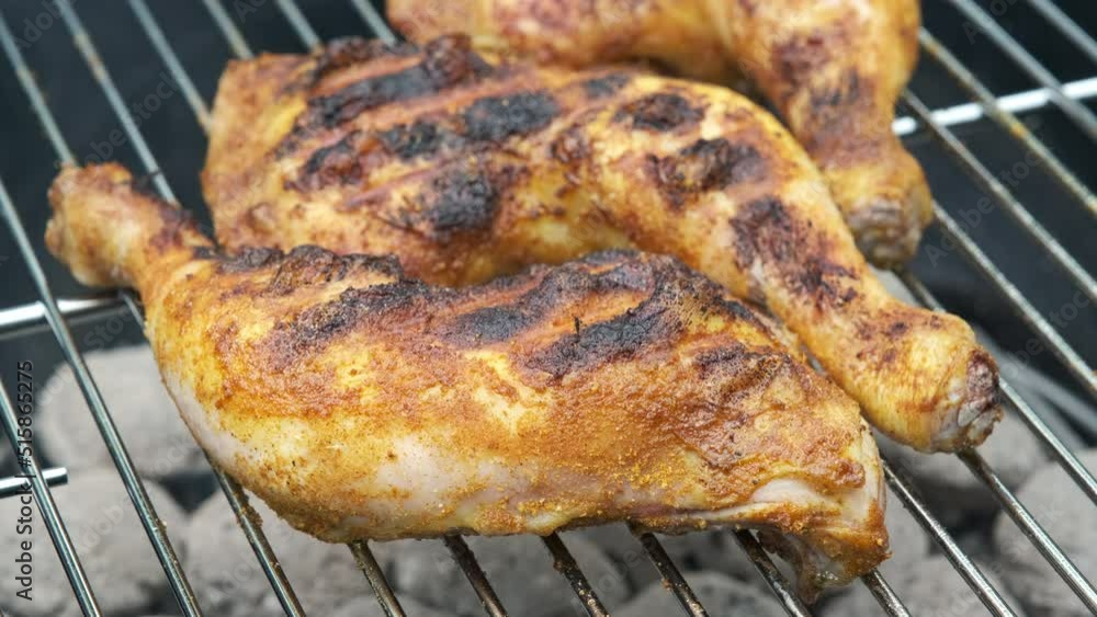 Closeup of barbeque with three spiced chicken legs on smoldering briquettes. Smoking bbq with grilled well-done chicken meat. Closeup of barbeque with three spiced chicken legs on smoldering briquettes. Smoking bbq with grilled well-done chicken meat.