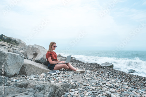 Remote work.Girl freelancer works remotely on the seashore.workation  remote work WFVH Van Life vibes work from vacation home work travel remotely work.Travelling