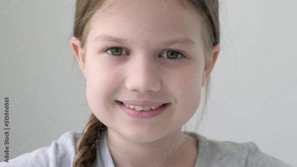 Headshot portrait of smiling little girl isolated on grey background. Child looking at camera, happy small elementary school pupil in gray t-shirt posing feel overjoyed Headshot portrait of smiling little girl isolated on grey background. Child looking at camera, happy small elementary school pupil in gray t-shirt posing feel overjoyed