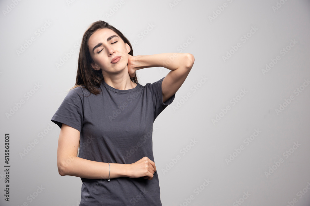 Image of a young pretty woman holding hand on neck Image of a young pretty woman holding hand on neck