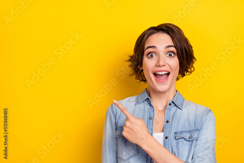 Photo of young excited girl indicate finger empty space ads decision select discount isolated over yellow color background photo