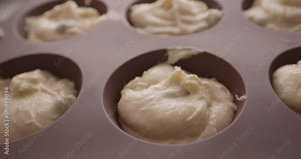 The chef puts the finished dough into cupcake or MUFFINS molds. Close-up. The chef puts the finished dough into cupcake or MUFFINS molds. Close-up.