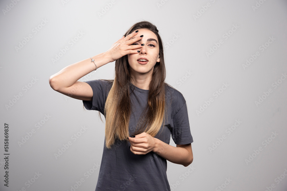 Portrait of young woman touching her face posing over gray background Portrait of young woman touching her face posing over gray background