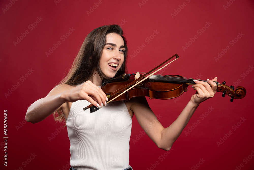 Young beautiful woman playing the violin on a red background Young beautiful woman playing the violin on a red background