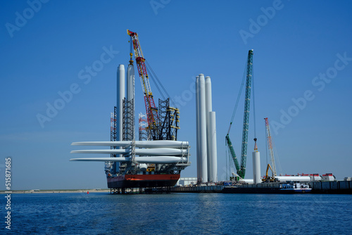 A large offshore vessel with a crane and a helipad is moored in the seaport of Rotterdam. A Jack-up vessel for use in the offshore wind industry