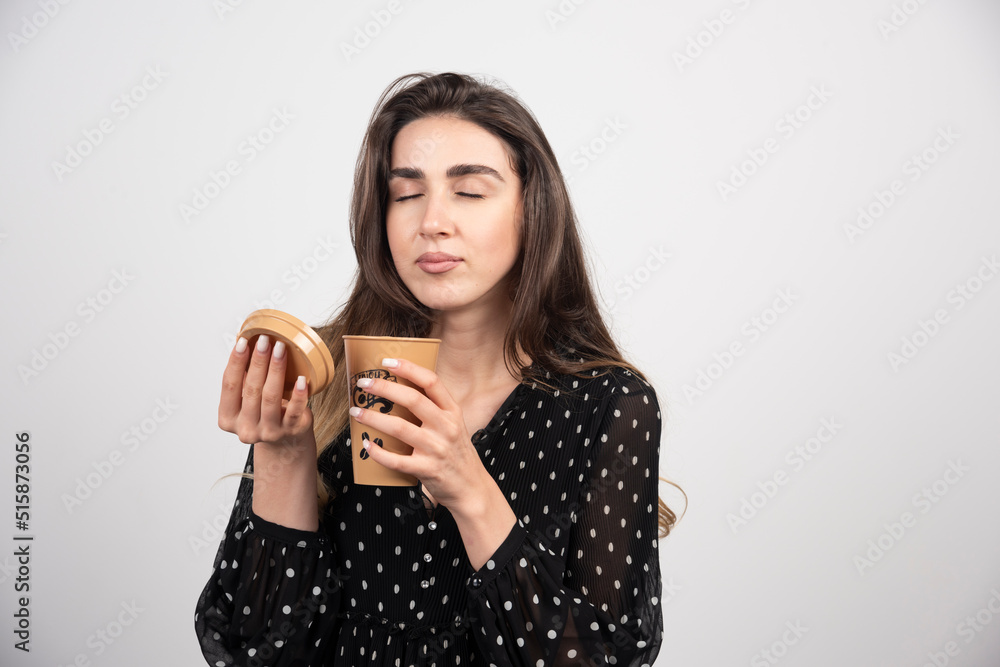 Young woman model sniffing from coffee cup on a white background Young woman model sniffing from coffee cup on a white background