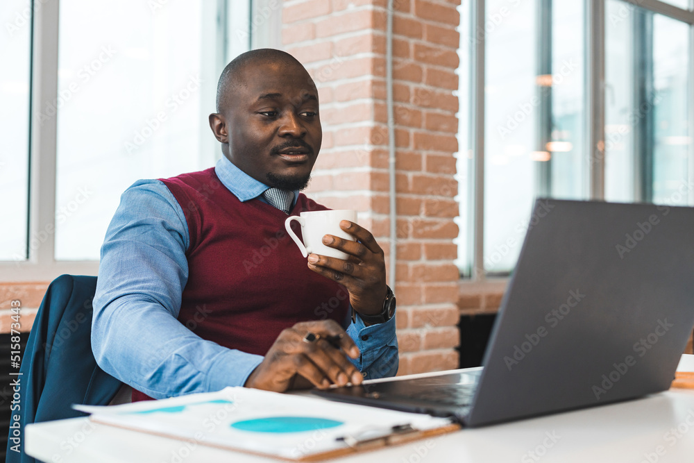 Portrait of an African American in the office. Black man in a business suit working on a laptop Portrait of an African American in the office. Black man in a business suit working on a laptop