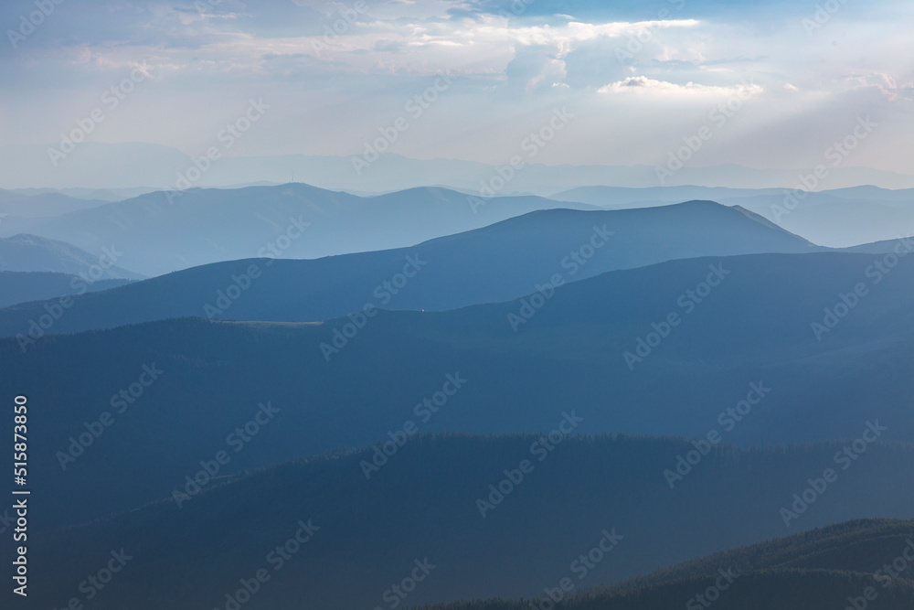 Panoranic blue view of mountain hills and meadows during sunset