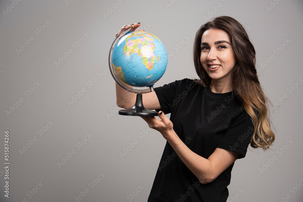 Happy woman holding globe on gray background Happy woman holding globe on gray background