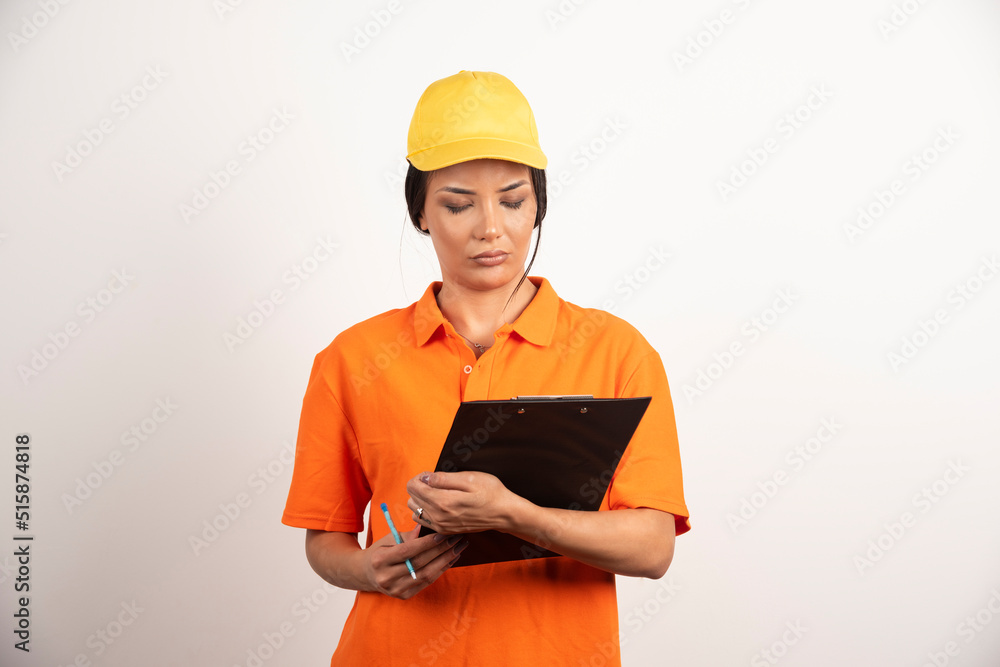 Serious woman courier with pencil looking on clipboard on white background Serious woman courier with pencil looking on clipboard on white background