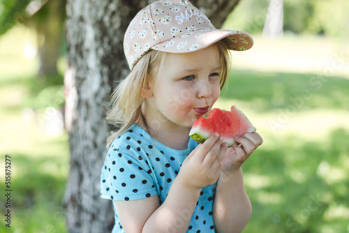 cute little girl eating watermelon outdoors in summertime. Child and watermelon in summer. 