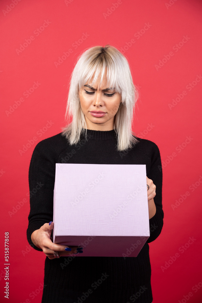 Naklejka premium Young woman with present on a red background
