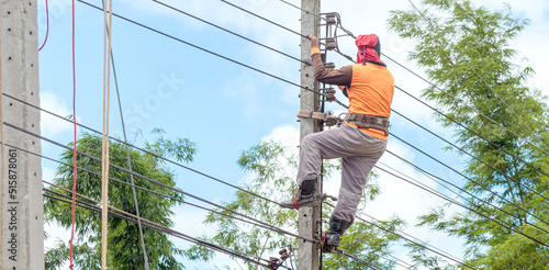 Electrician lineman repairman worker at climbing work on electric post power pole