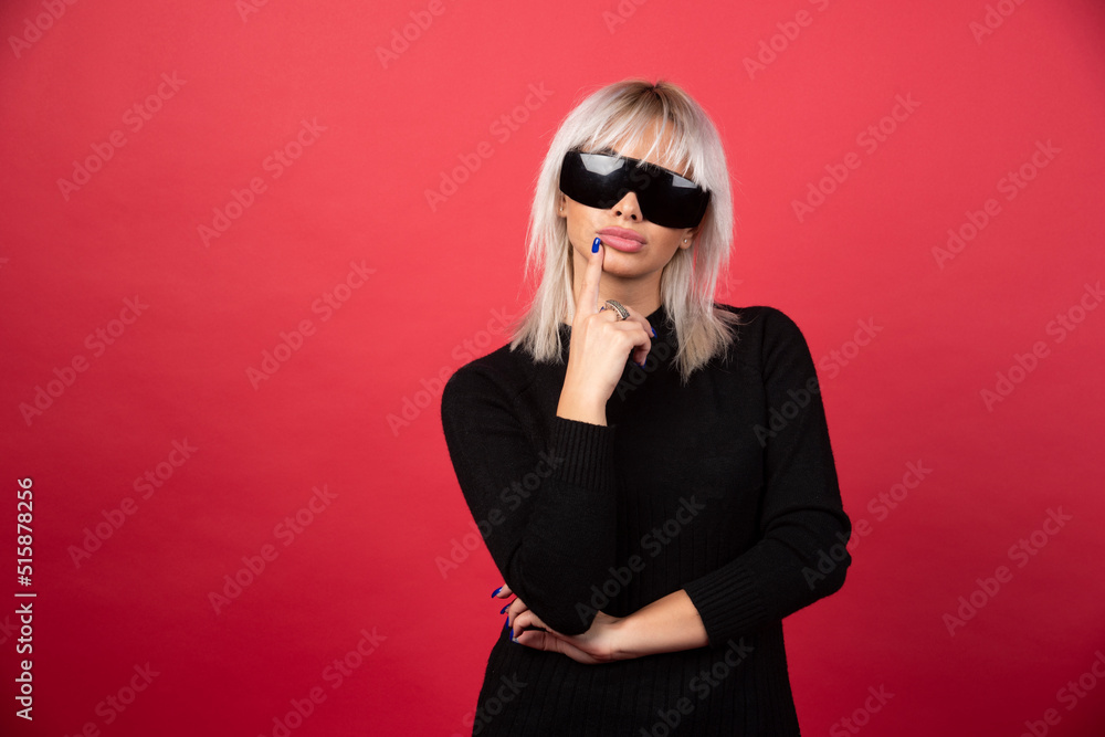 Portrait of woman standing and posing with a black glasses on a red background Portrait of woman standing and posing with a black glasses on a red background