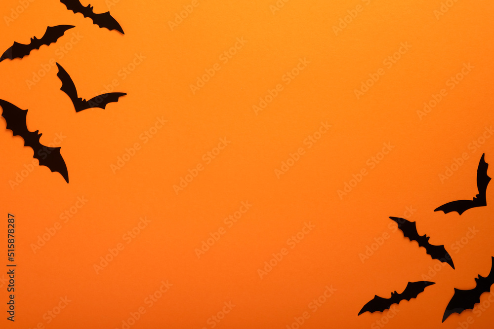 Orange Halloween background. Flock of black bats for Halloween. Black paper bat silhouettes on orange background. Halloween concept, Copy space, top view, overhead. Orange Halloween background. Flock of black bats for Halloween. Black paper bat silhouettes on orange background. Halloween concept, Copy space, top view, overhead.