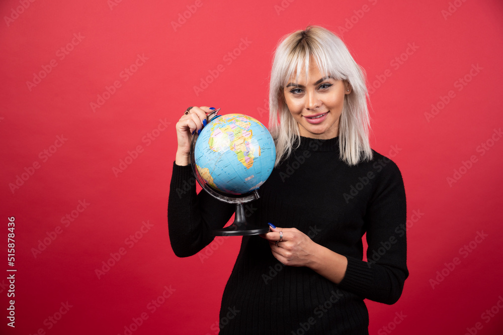 Portrait of woman holding an Earth globe on a red background Portrait of woman holding an Earth globe on a red background