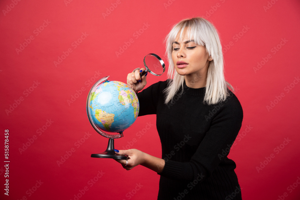 Portrait of woman holding a magnifying glass and Earth globe